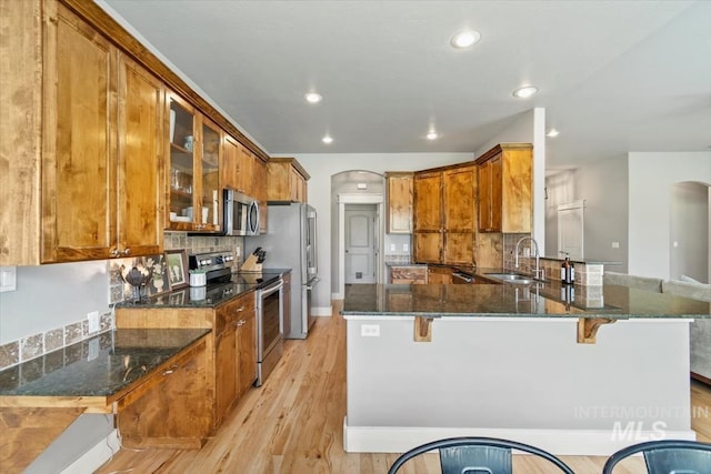 12231 W Caribee Inlet Dr, Star, ID 83669 - kitchen with stainless steel appliances, arched walkways, brown cabinetry, dark stone countertops, and recessed lighting