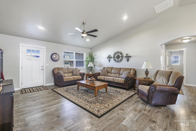 living area featuring arched walkways, visible vents, lofted ceiling, and wood finished floors