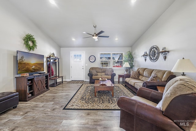 living area with baseboards, wood finished floors, a ceiling fan, and vaulted ceiling