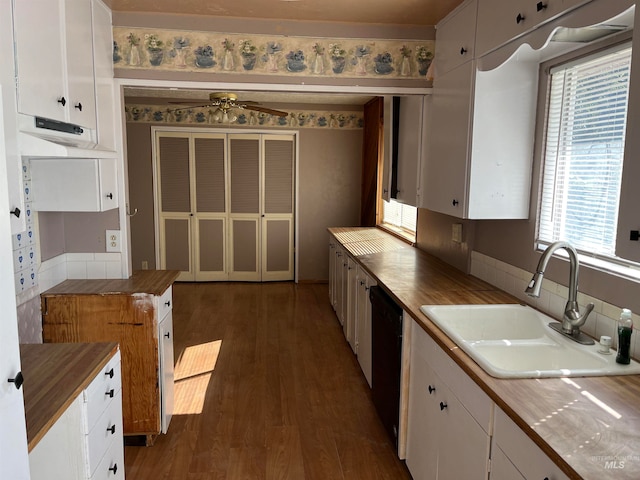 kitchen with black dishwasher, sink, white cabinets, and dark wood-type flooring