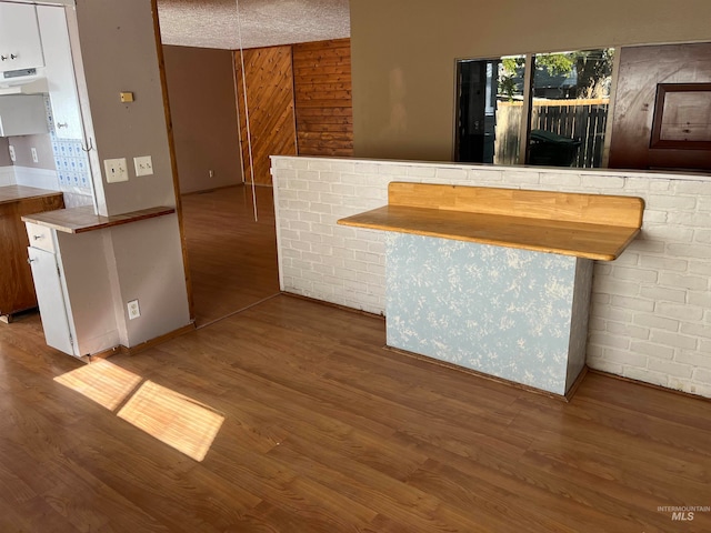 bar featuring white cabinets, a textured ceiling, wood-type flooring, and range hood