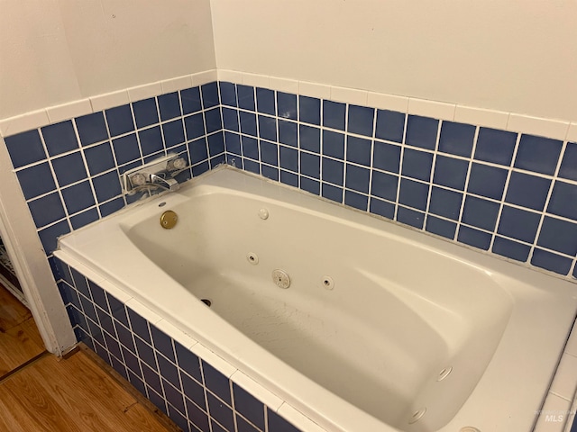 bathroom featuring tiled tub and hardwood / wood-style floors