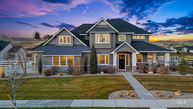 craftsman inspired home featuring a front yard, fence, and stone siding