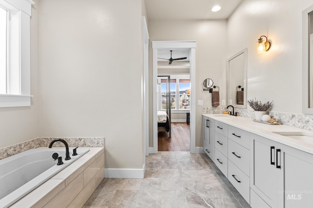 bathroom featuring a garden tub, a sink, ensuite bath, double vanity, and ceiling fan