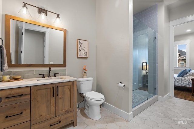 ensuite bathroom with a stall shower, toilet, vanity, and baseboards