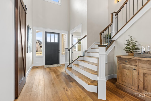 foyer entrance with a high ceiling, light wood-style flooring, and stairs