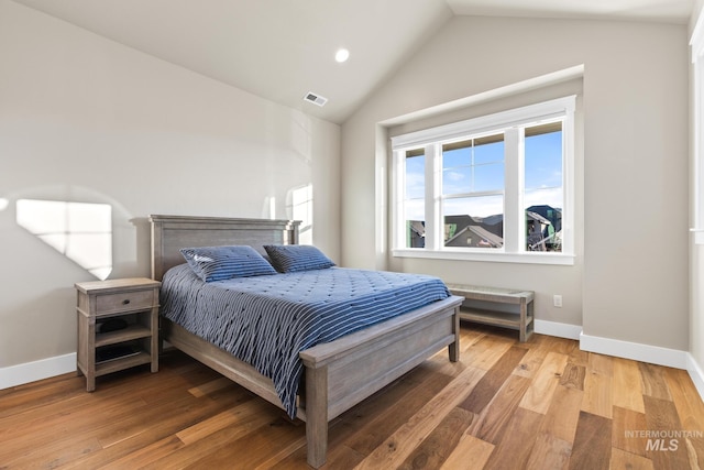 bedroom with visible vents, baseboards, light wood-style floors, and vaulted ceiling