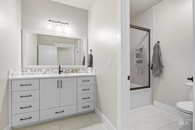 bathroom featuring baseboards, toilet, enclosed tub / shower combo, marble finish floor, and vanity