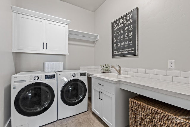 laundry area with light wood finished floors, cabinet space, independent washer and dryer, and a sink