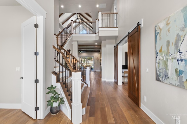 foyer featuring a barn door, wood finished floors, baseboards, and a towering ceiling