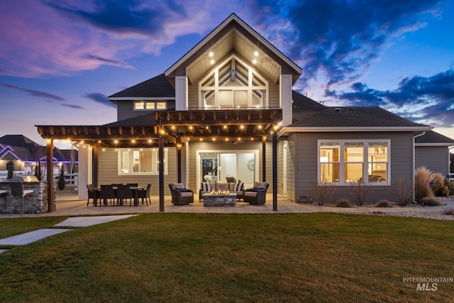 rear view of property featuring a lawn, area for grilling, an outdoor living space with a fire pit, roof with shingles, and a patio area