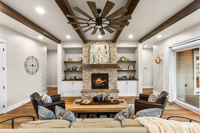 living area with a ceiling fan, beamed ceiling, wood finished floors, and baseboards