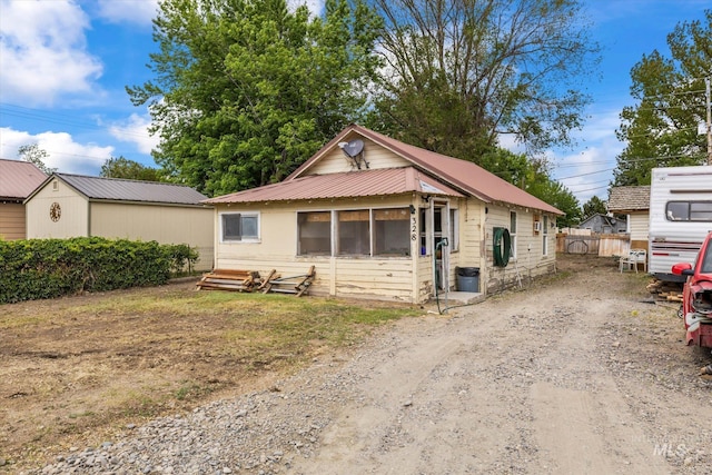 328 W Owyhee Ave, Homedale, ID 83628 - view of front facade with dirt driveway, metal roof, a sunroom, and fence