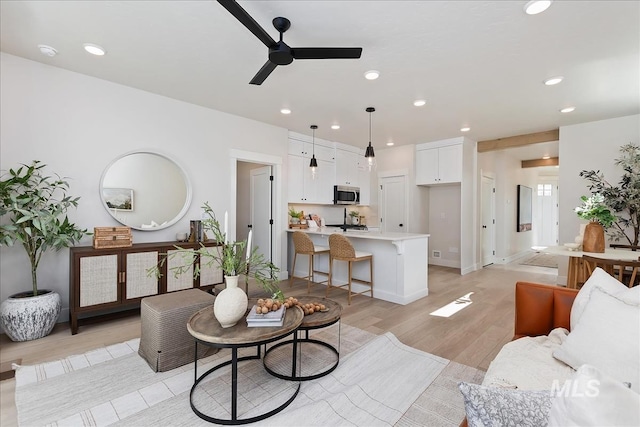 living room featuring baseboards, recessed lighting, a ceiling fan, and light wood-style floors