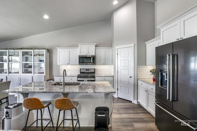 kitchen with a kitchen bar, a sink, white cabinets, and stainless steel appliances