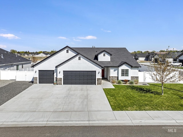 modern farmhouse style home with a front lawn, a garage, driveway, stone siding, and fence