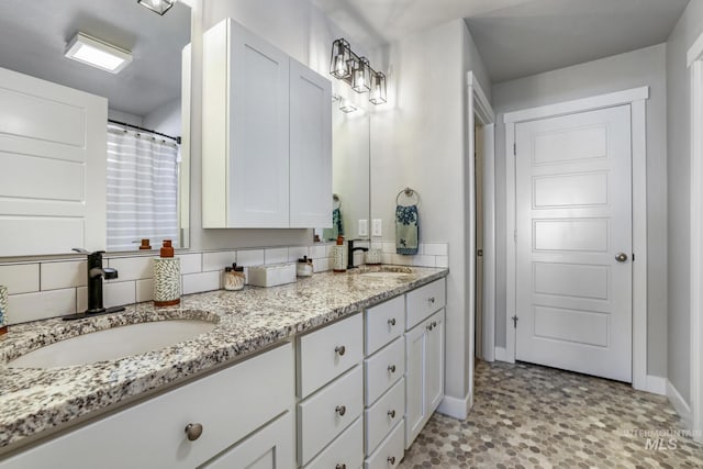 full bathroom featuring double vanity, baseboards, and a sink
