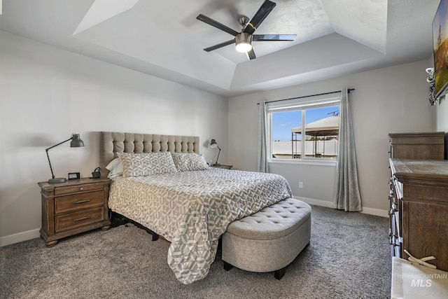 bedroom with carpet flooring, a tray ceiling, a ceiling fan, and baseboards