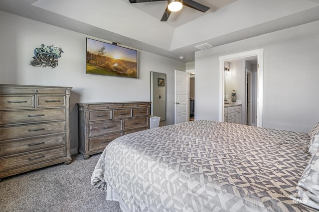 carpeted bedroom with visible vents, ceiling fan, a raised ceiling, and ensuite bathroom