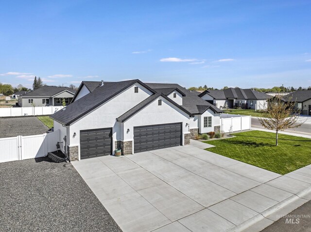 modern farmhouse style home featuring a gate, a residential view, stone siding, a front lawn, and an attached garage