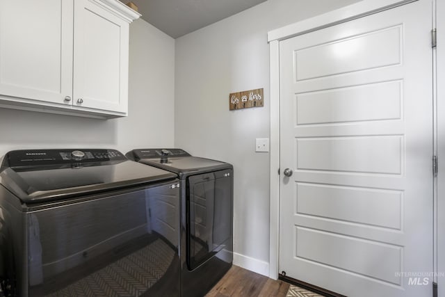 clothes washing area featuring dark wood finished floors, separate washer and dryer, cabinet space, and baseboards