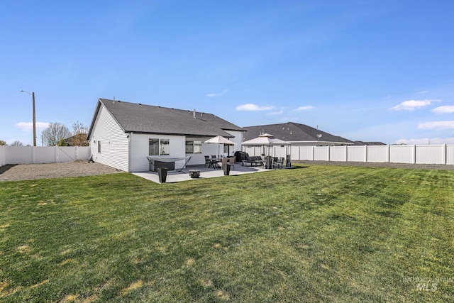 rear view of house featuring a lawn, a fenced backyard, and a patio area