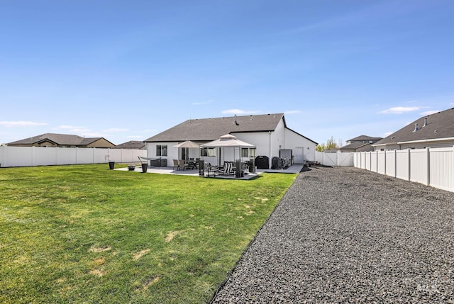 back of house with a lawn, a patio area, a shingled roof, and a fenced backyard