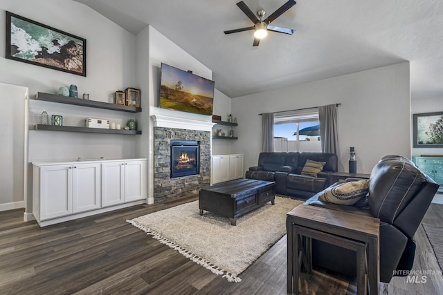 living room featuring lofted ceiling, dark wood-type flooring, a ceiling fan, and a stone fireplace