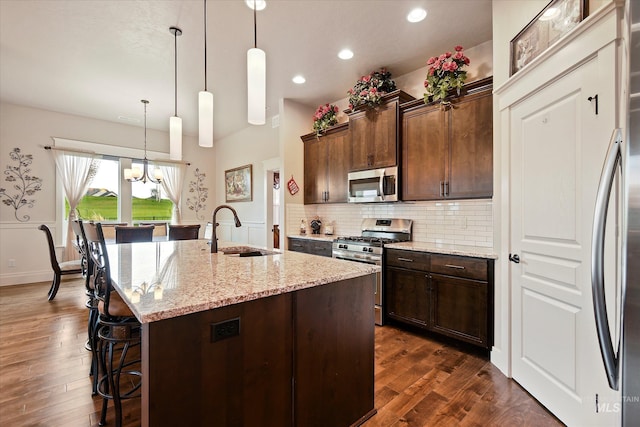11771 W Cross Slope Way, Nampa, ID 83686 - kitchen featuring light stone countertops, a sink, dark wood-style flooring, a breakfast bar, and appliances with stainless steel finishes