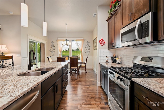 11771 W Cross Slope Way, Nampa, ID 83686 - kitchen with light stone counters, a sink, stainless steel appliances, an inviting chandelier, and dark wood finished floors