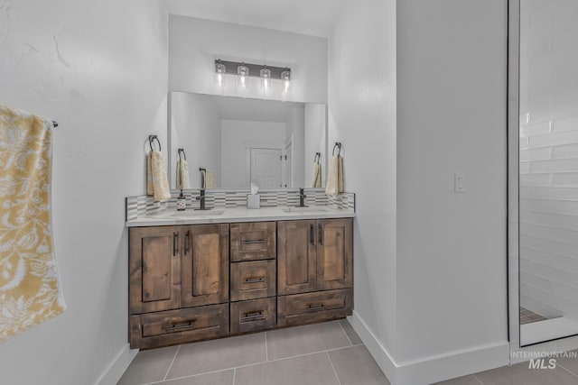 bathroom with tile patterned floors, double vanity, baseboards, and tasteful backsplash