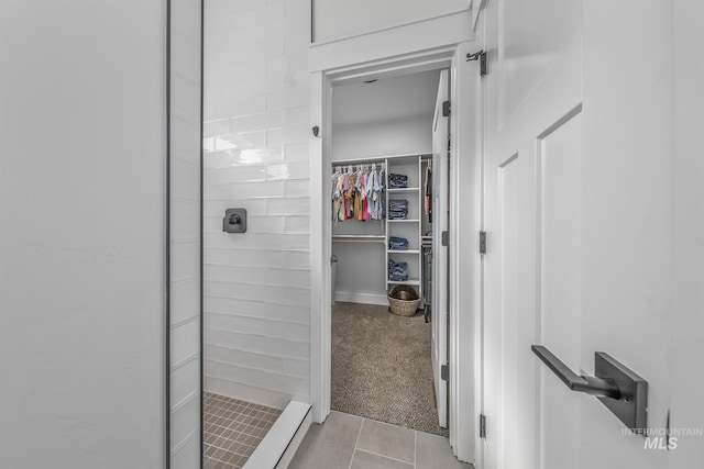 full bathroom featuring a stall shower, a walk in closet, and tile patterned floors