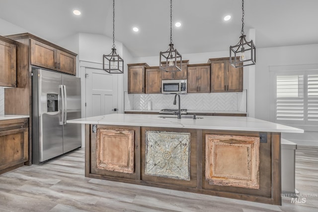 kitchen with appliances with stainless steel finishes, tasteful backsplash, a kitchen island with sink, light wood-style flooring, and recessed lighting
