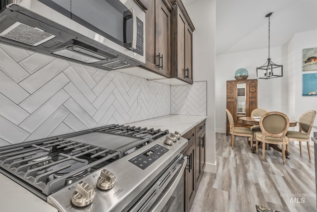 kitchen featuring stainless steel appliances, dark brown cabinetry, decorative backsplash, and light wood finished floors