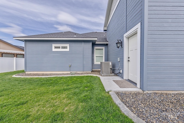 rear view of property featuring cooling unit and roof with shingles