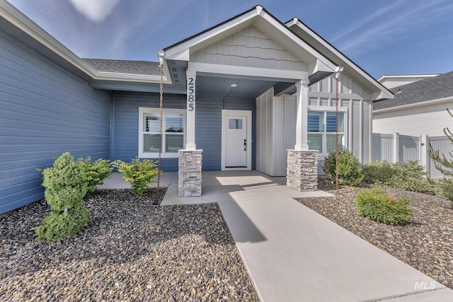 entrance to property featuring fence, a porch, and board and batten siding