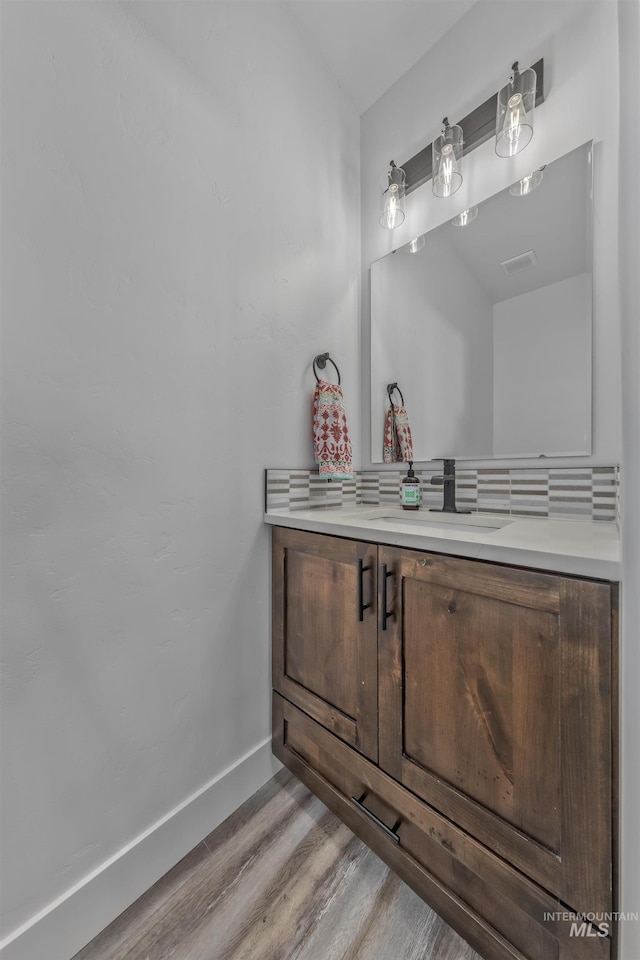 bathroom with wood finished floors, baseboards, and vanity