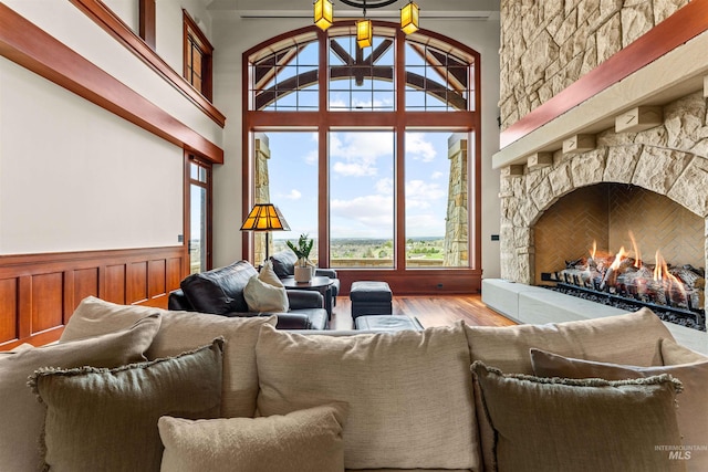 living room with light wood-type flooring, a fireplace, and a towering ceiling