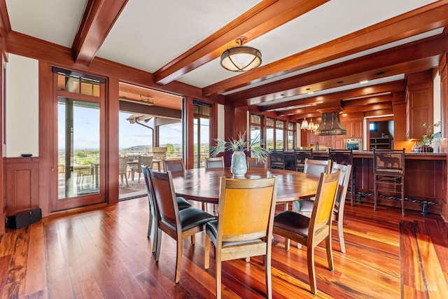 dining space with beam ceiling, plenty of natural light, and light hardwood / wood-style floors