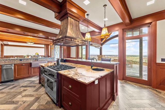 kitchen featuring beam ceiling, light stone counters, decorative light fixtures, a kitchen island with sink, and appliances with stainless steel finishes