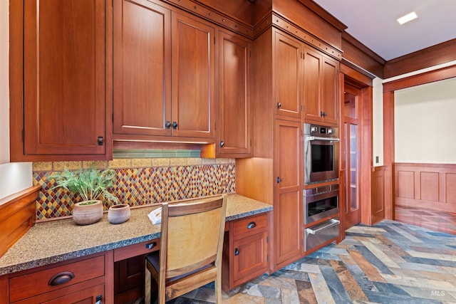 kitchen featuring light stone countertops, decorative backsplash, and stainless steel double oven