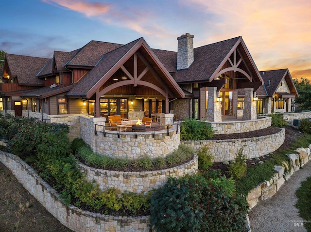 back house at dusk with an outdoor living space with a fire pit