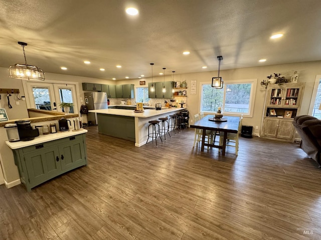 kitchen featuring light countertops, a kitchen bar, dark wood finished floors, and green cabinetry