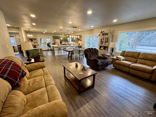 living room with french doors, dark wood finished floors, recessed lighting, an inviting chandelier, and a textured ceiling