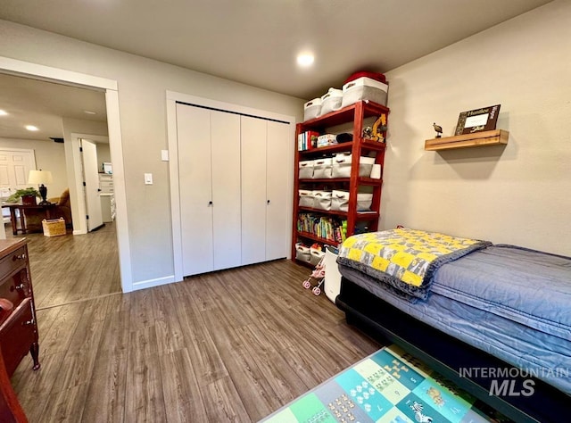 bedroom featuring a closet, baseboards, wood finished floors, and recessed lighting