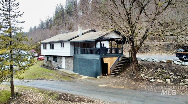 view of side of home featuring a deck, stone siding, and stairway