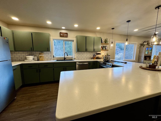 kitchen with stainless steel appliances, dark wood-style flooring, green cabinetry, and a sink