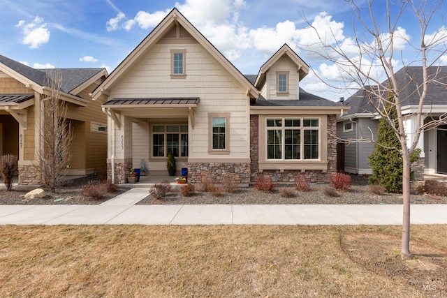 view of front of property with stone siding, a front yard, metal roof, and a standing seam roof