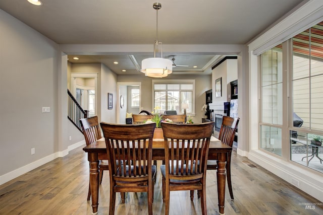 dining space featuring a fireplace, baseboards, wood finished floors, and recessed lighting