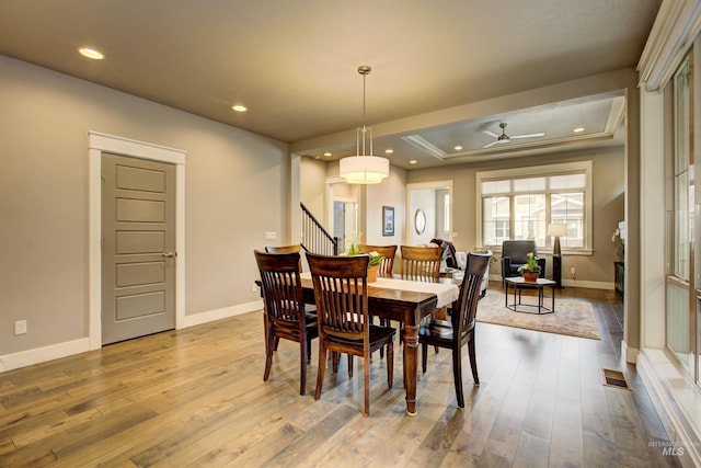 dining area with baseboards, a tray ceiling, visible vents, and hardwood / wood-style floors